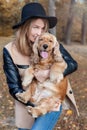 Beautiful cute happy girl in a black hat playing with her dog Royalty Free Stock Photo