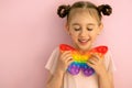 A beautiful cute little girl with her eyes closed holds a butterfly-shaped popit toy Royalty Free Stock Photo