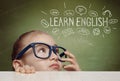 Beautiful cute little girl hiding under table and curiously looking at the illustrations and words in english above her head Royalty Free Stock Photo