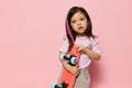 a beautiful cute little girl of preschool age is standing on a pink background in a pink T-shirt and a pink strand in Royalty Free Stock Photo