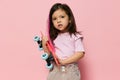 a beautiful cute little girl of preschool age is standing on a pink background in a pink T-shirt and a pink strand in Royalty Free Stock Photo