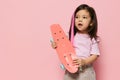 a beautiful cute little girl of preschool age is standing on a pink background in a pink T-shirt and a pink strand in Royalty Free Stock Photo