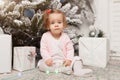 Beautiful cute little girl sitting on the floor near the New Year tree. Holiday mood, childlike spontaneity and sweet atmosphere Royalty Free Stock Photo