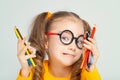 Beautiful cute little preschooler girl holding colorful pencils and making gesture while looking at camera. Playful child with pen Royalty Free Stock Photo