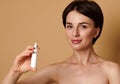 Beautiful cute smiling Caucasian woman cute smiles looking at camera, holding nasal spray isolated on beige background with copy Royalty Free Stock Photo