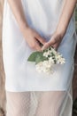 Beautiful cute tender girl with dark hair in a white summer dress with a jasmine flower in hands