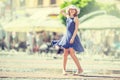 Beautiful cute young girl dancing on the street from happiness.Cute happy girl in summer clothes dancing in the sun