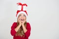 Beautiful cute young girl in red dress and santa hat with gift on head looking above. Excited surprised child with present Royalty Free Stock Photo