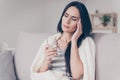 Beautiful cute young woman touches her temple and feels a strong headache holding a glass of water in her hand Royalty Free Stock Photo