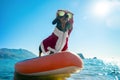 Beautiful dachshund dog in sunglasses for pets and Santa costume is on stiffest durable SUP board in sea or ocean ready