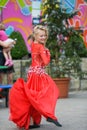 Beautiful dancer in a red dress. Beautiful young girl dancing in a red dress. Dance in public. Talented kid does dancing