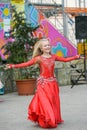 Beautiful dancer in a red dress. Beautiful young girl dancing in a red dress. Dance in public. Talented kid does dancing