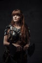 Beautiful woman viking with two handed axe in dark background