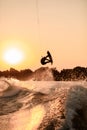 beautiful dark silhouette of man holding rope and making jump on wakeboard at sunset. Royalty Free Stock Photo