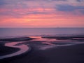 Beautiful dark twilight over a calm flat sea with purple sky and blue clouds reflected in water on the beach Royalty Free Stock Photo