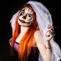 Beautiful dead bride with terrible mask painted on her face. Halloween and creative make-up. Royalty Free Stock Photo