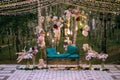 Beautiful decor of natural flowers, feathers and garlands, small lights at the evening party, decorative bench Royalty Free Stock Photo