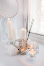 Beautiful decor of white lighted candles in glass candlesticks stand on windowsill, relax place in house, concept of winter cozy Royalty Free Stock Photo