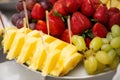 Decorated various fruits on plate at restaurant, wedding catering. Pineapple, strawberry, green grape.