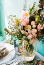 Beautiful decorated wedding table with bridal bouquet, flowers, glass, candles