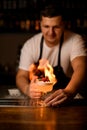 beautiful decorative heart on glass with foamy cocktail on the bar and male bartender with fire on background