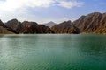 Beautiful deep green Hatta lake with rocky Hajar Mountains on background
