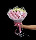 Beautiful delicate bouquet consisting of strawberries in pink chocolate and white roses in female hand on a black background Royalty Free Stock Photo