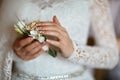 Beautiful delicate wedding boutonier with white flowers in the hands of the bride, lace dress, morning of the bride