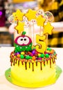 beautiful delicious chocolate cake. lots of yellow decorations on the cake. 5 candles. cookie figures