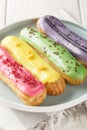 Beautiful delicious french eclairs set with original cream decor on wooden background. Vertical