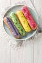 Beautiful delicious french eclairs set with original cream decor on wooden background. Vertical top view