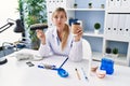 Beautiful dentist woman holding denture and toothbrush puffing cheeks with funny face Royalty Free Stock Photo