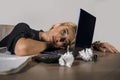 Beautiful depressed sad blonde woman working with laptop computer feeling tired sitting at office desk overwhelmed by paperwork su