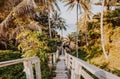 A beautiful descent wooden staircase through the jungle down to the beach. A beautiful view opens through palm trees to the ocean