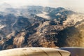 Beautiful detail of mountains from a window of a flying airplane. Aerial view of terrain.