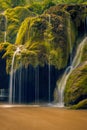 Beautiful detail of a waterfall flowing onto a moss covered rock with a cave beneath Royalty Free Stock Photo