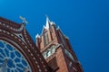 Beautiful details of steeples and rose window, Gothic Revival church, red brick white crosses, blue sky