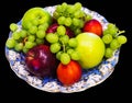 Beautiful dish covered with blue with gilded patterns with fruit - apples, grapes and peaches Royalty Free Stock Photo