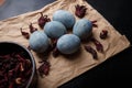 Beautiful DIY painted Easter eggs, dry Hibiscus tea in black bowl. Easter black wooden background. Close up shot Royalty Free Stock Photo