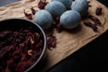 Beautiful DIY painted Easter eggs, dry Hibiscus tea in black bowl. Easter black wooden background. Close up shot Royalty Free Stock Photo