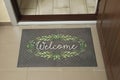 Beautiful doormat with word Welcome on floor near entrance, above view