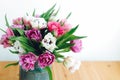 Beautiful double peony tulips in light. Colorful pink and purple tulips bouquet in vase on table with copy space. Happy mothers