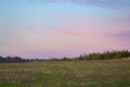 Beautiful dramatic purple, pink, blue and orange cloud and sky after storm and rain over agricultural field on countryside in Royalty Free Stock Photo