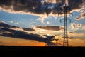 Beautiful dramatic sky and clouds, sunset lights over the transmission tower electricity pylon on a field Royalty Free Stock Photo