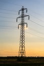 Beautiful dramatic sky and clouds, sunset lights over the transmission tower electricity pylon on a field Royalty Free Stock Photo