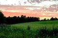 Beautiful dramatic sky colorful orange clouds sunset over forest and meadow. Landscape panoramic view. Royalty Free Stock Photo