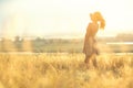 Beautiful girl walking in a field in a dress at sunset, a young woman enjoying summer nature Royalty Free Stock Photo