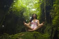 Beautiful dreamy portrait of young attractive Asian woman enjoying nature sitting lotus pose doing yoga meditating relaxed at Royalty Free Stock Photo