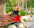 Beautiful dreamy woman on bench in city park in summer