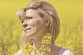 Beautiful dreamy woman in a rapeseed field with a bouquet dreams and enjoys nature. Royalty Free Stock Photo